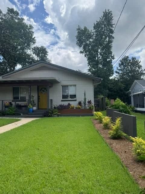 This bungalow on Talaflo Street features a lush lawn, planters out front and a row of green-yellow bushes on the side yard.