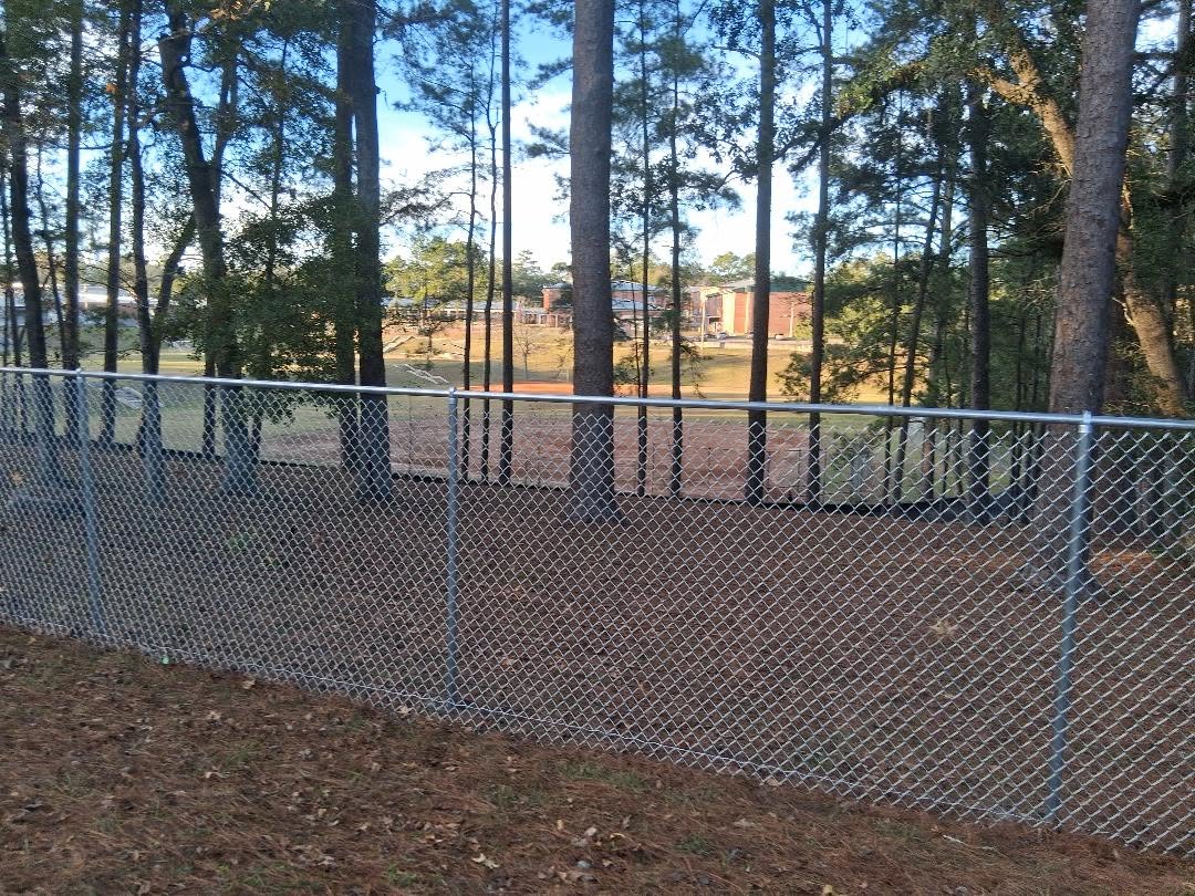A large sunken field for playing soccer, baseball and other recreation is surrounded by a chain link fence.